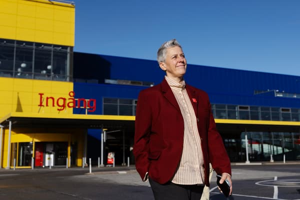 En kvinna i röd kavaj står utanför ett IKEA-varuhus.