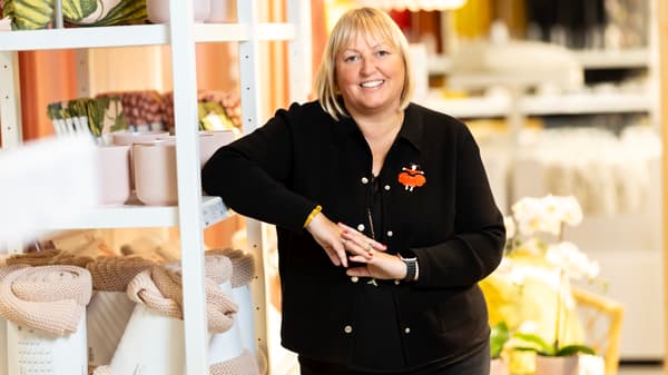 En kvinna i svarta kläder står lutad mot en vit hylla med IKEA-produkter.