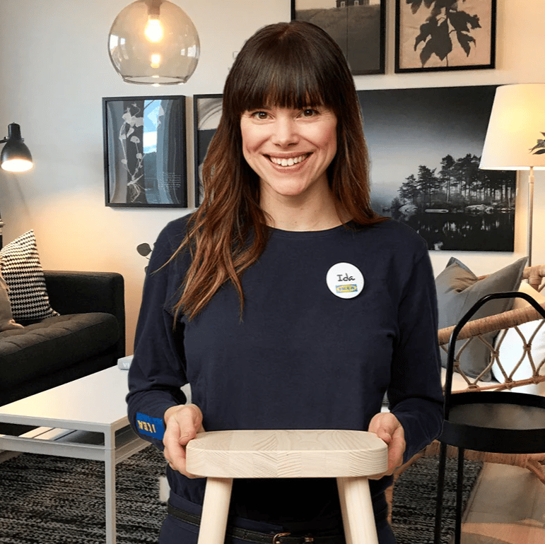 En kvinna med brunt hår står och håller en pall.