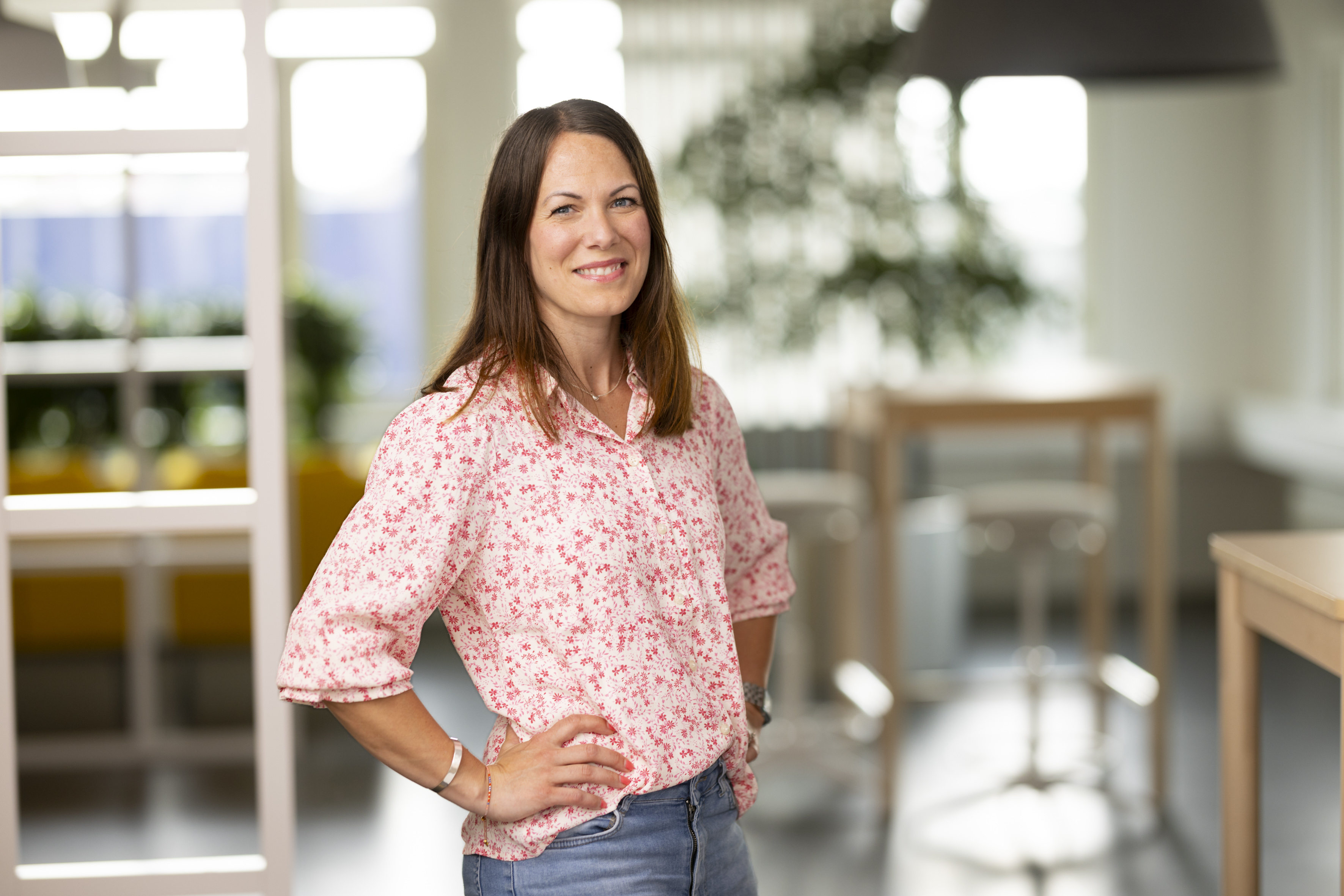 En kvinna med mörkt hår står i en kontorsmiljö.