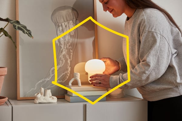 En kvinna sätter en liten bordslampa på ett bord.