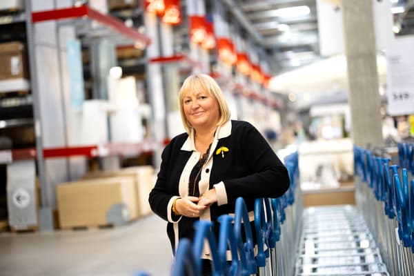 En kvinna står i ett tag-själv-lager på IKEA. Hon lutar sig mot en rad kundvagnar.