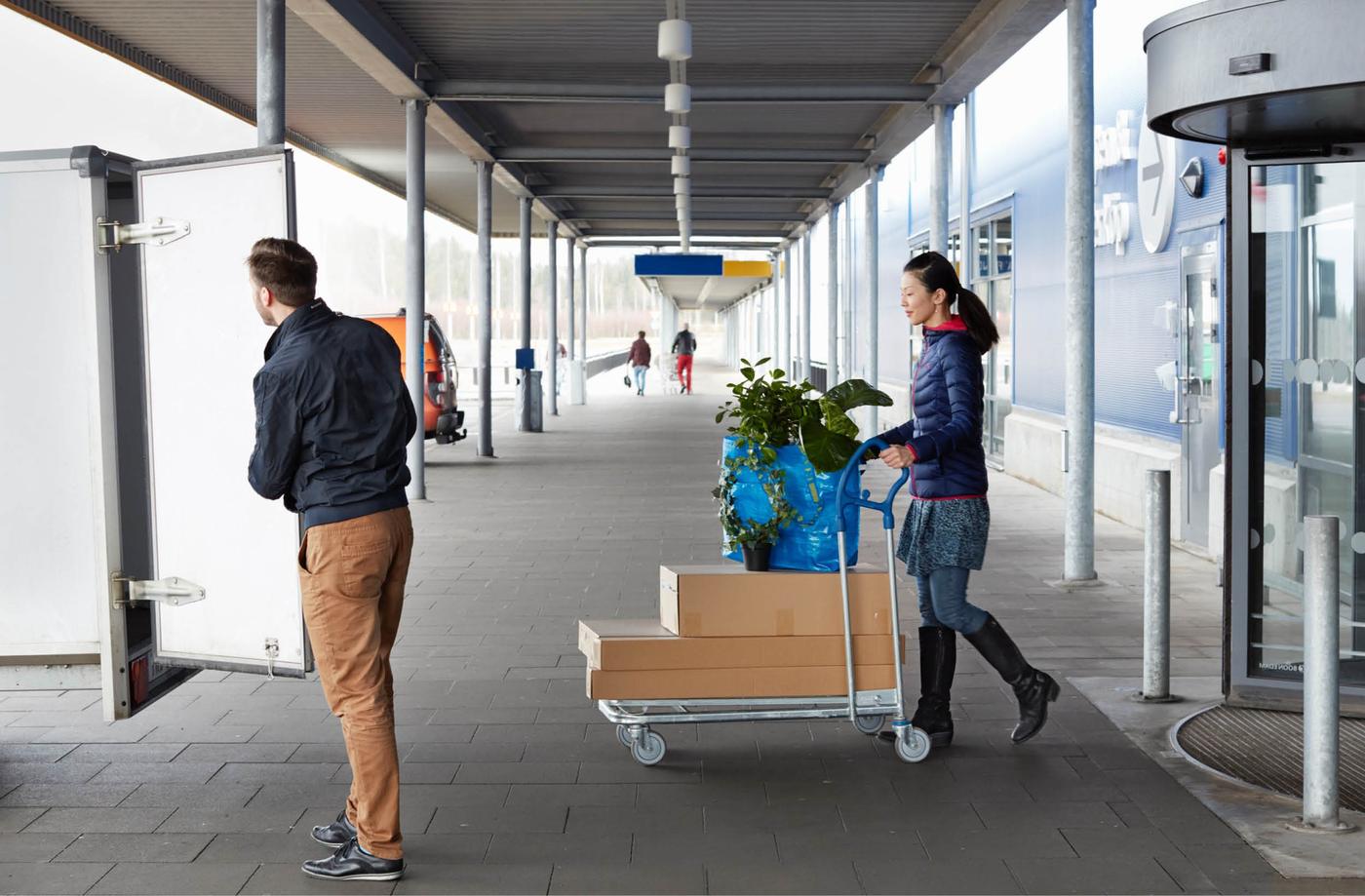 En kvinne med en varetralle og en mann på vei ut fra et IKEA varehus.