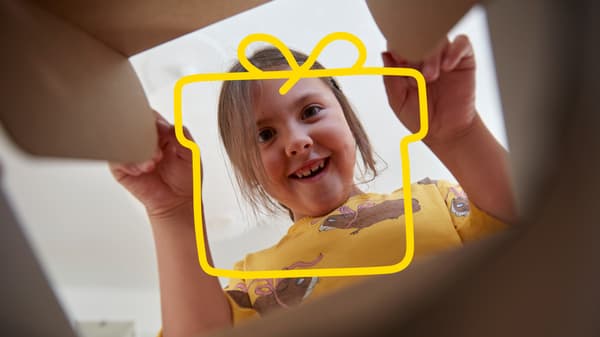 En liten flicka tittar ner i en låda.