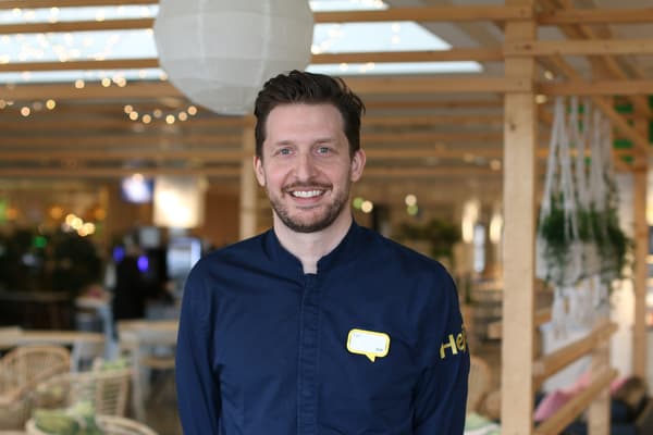 En man med skägg och blå IKEA kläder står i en IKEA restaurang.