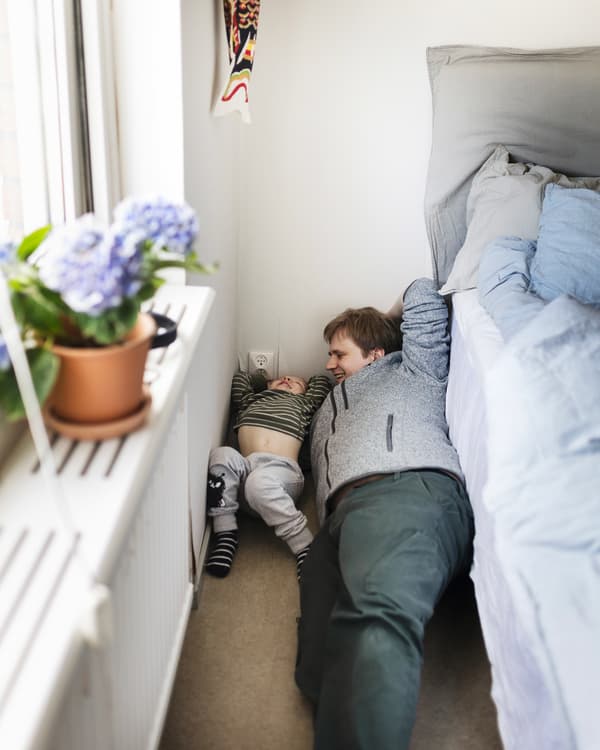 En man och en ett barn ligger på golvet och leker.