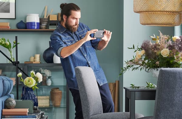En man som bruker mobilen for å ta bilder av møbler for å selge videre.