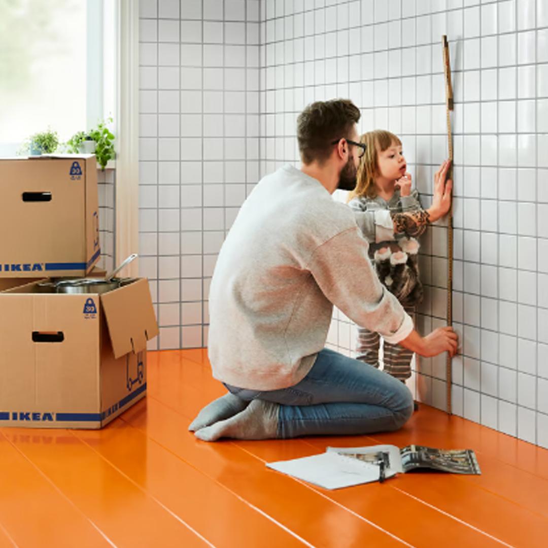 En mand og en lille pige er ved at måle et køkken op.