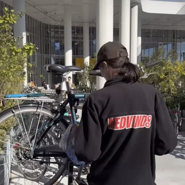 en mand står med ryggen til, og er ved at rengøre en cykel 