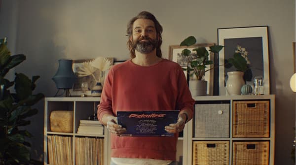 En mand står stolt og viser en gammel LP frem foran sine nyrestaurerede KALLAX reoler. 