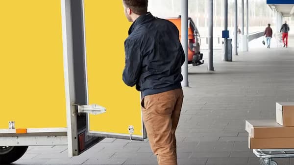 En mann åpner døra på en gul tiilhenger. 
