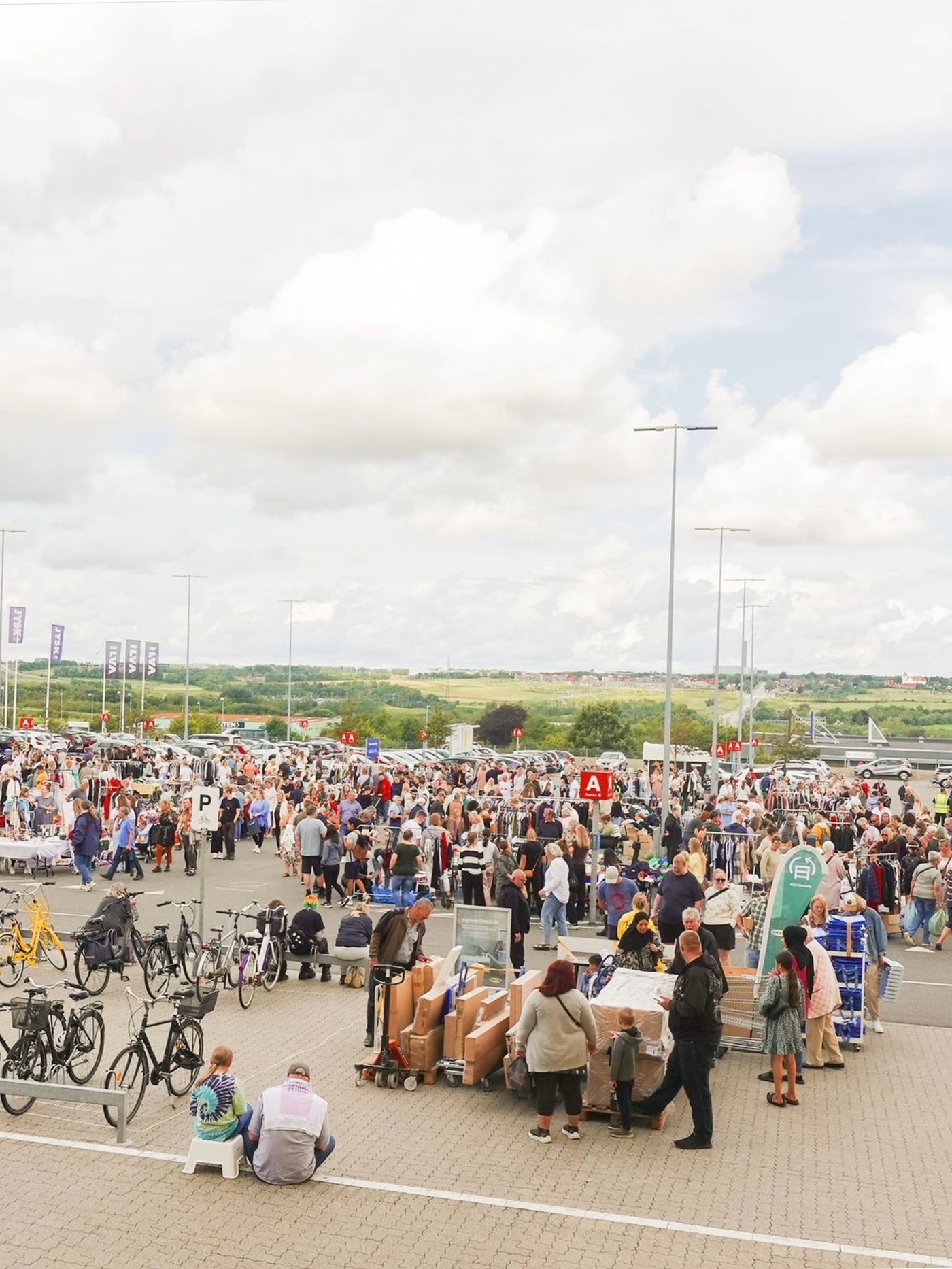 En masse mennesker på en parkeringsplads ved et IKEA loppemarked.