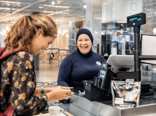 En medarbetare i hijab som hjälper en kund.