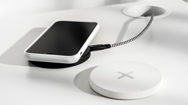 En mobiltelefon som ligger på en svart platta för trådlös laddning, bredvid finns en vit platta för trådlösladdning.