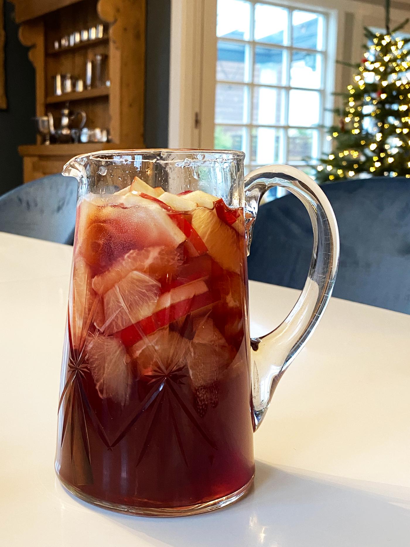 En mugge med rød gløgg og frukt oppi.