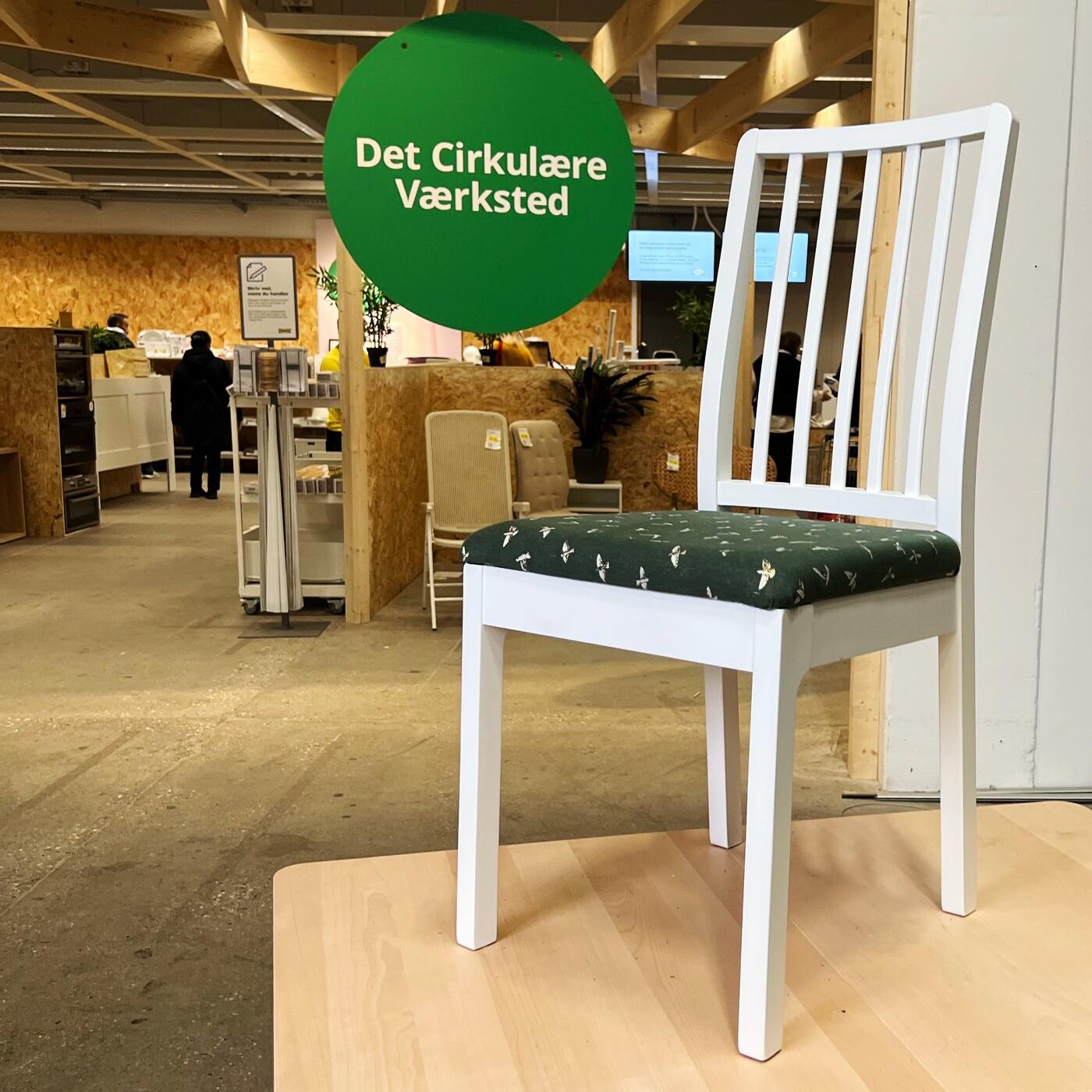 En ompolstret stol står på et bord foran Cirkulär i et IKEA varehus.