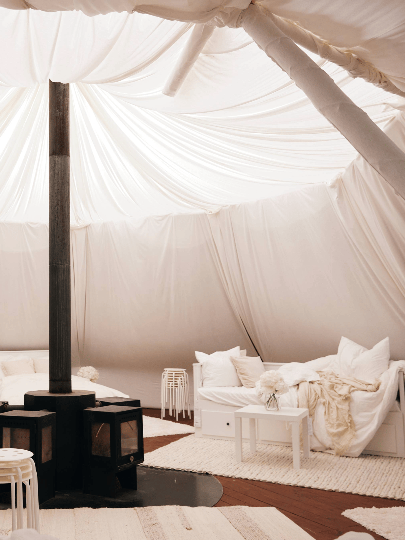 En ovn står i midten i en tribune med hvide lagner og HEMNES sovesofaer med hvidt sengetøj på.