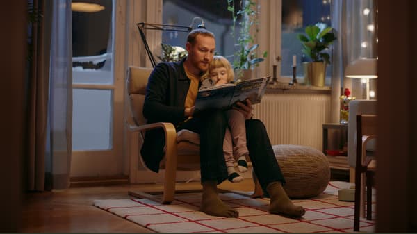 En pappa läser en saga för sin dotter i en POÄNG fåtölj. 