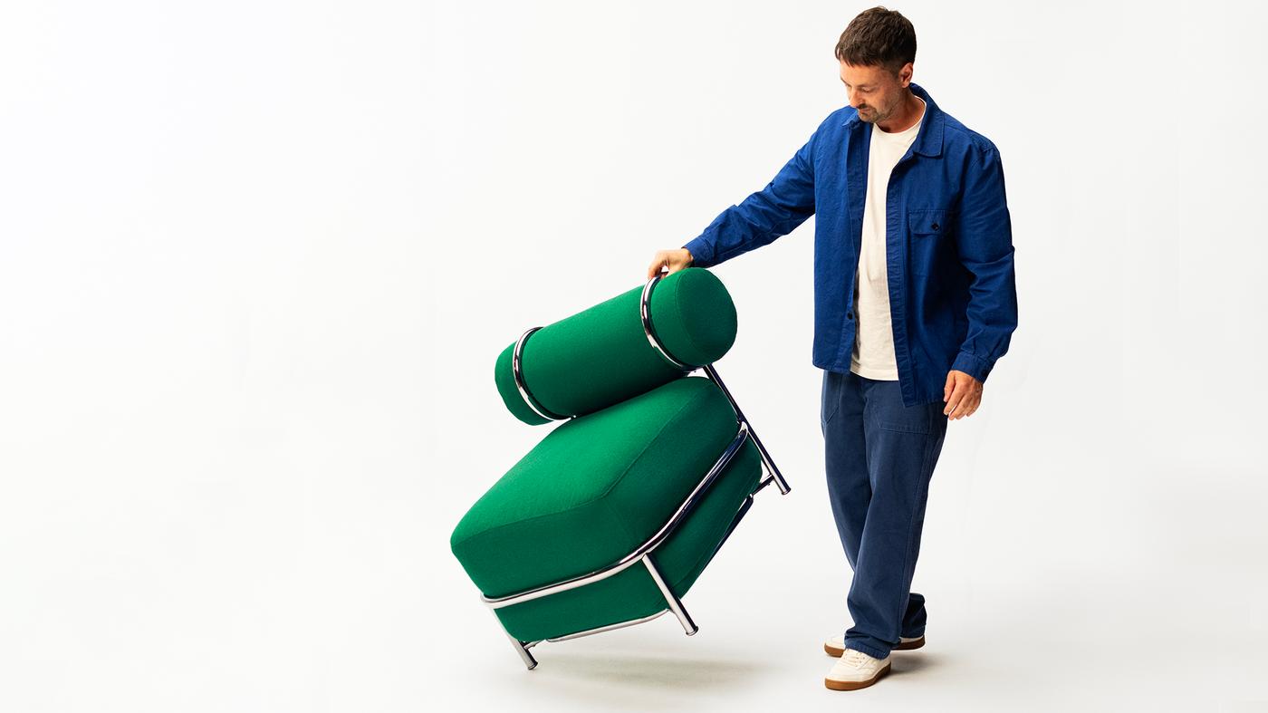 En person håller en grön fåtölj med ena handen. 