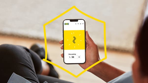 En person håller en mobil i handen som visar att han har samlat poäng IKEA Family.