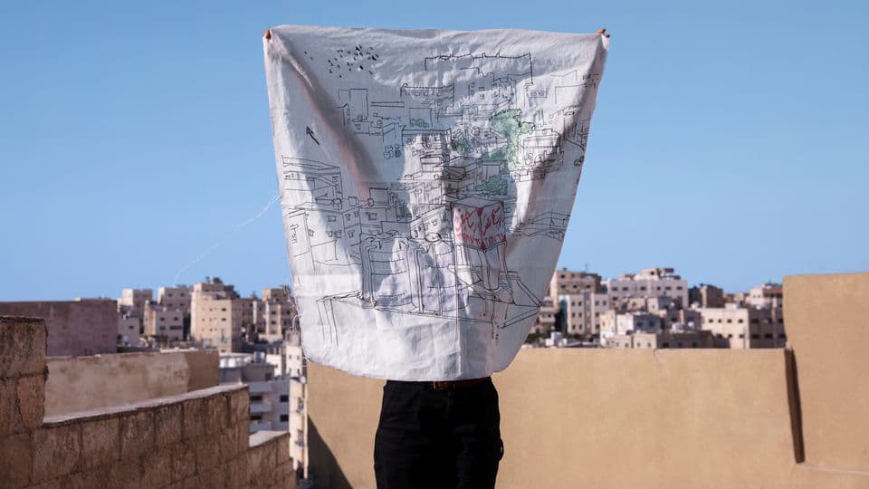 En person håller upp ett tygstycke med en ritning på