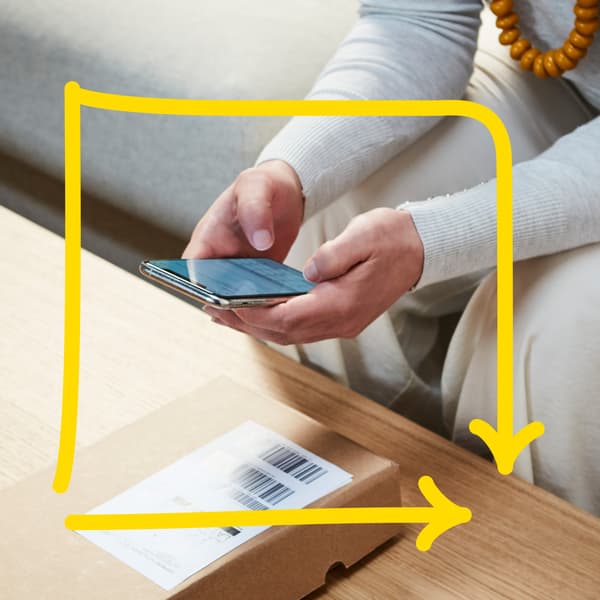 En person holder en mobil henover en kasse med et label på og scanner det henover billedet er en gul firkant igur.