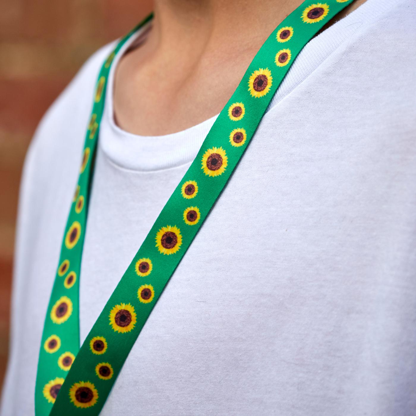 En person i hvid t-shirt bærer den grønne solsikkesnor omkring halsen.