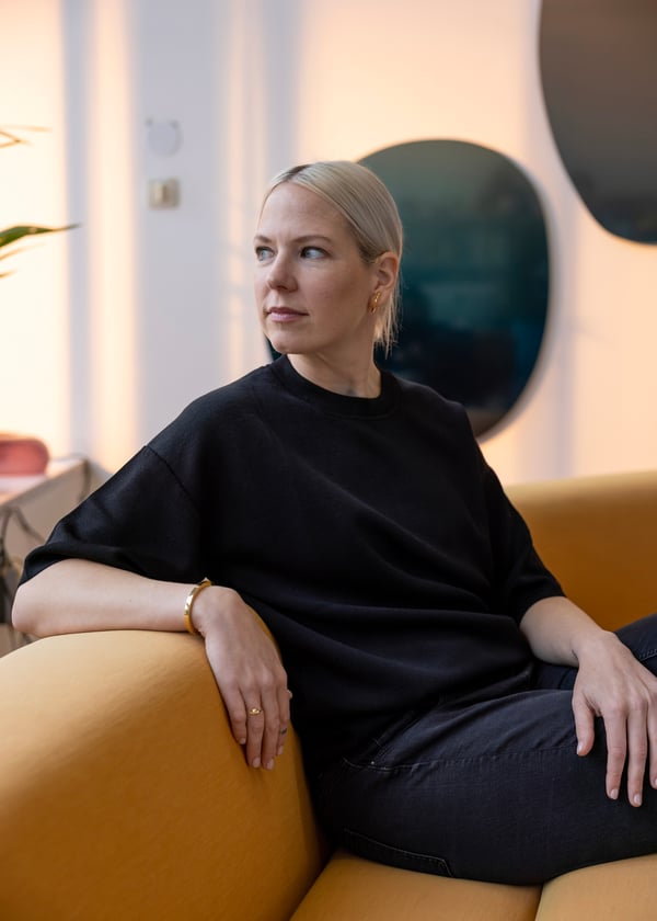 En person i svarta kläder sitter i en gul soffa. 