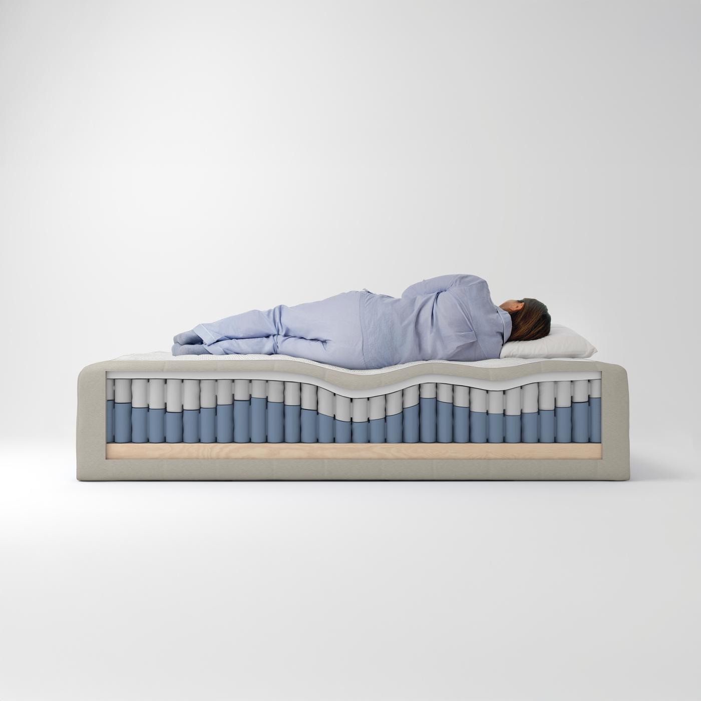 En person ligger och sover på en FJÄLLÅSEN resårmadrasskärna som har fått en del av sin träram bortskuren på ena sidan.
