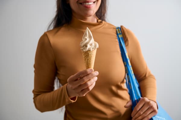 En person med mörkt beige tröja håller i en glasstrut. 