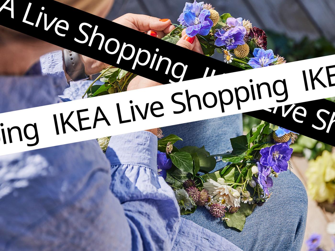 En person med nblå linneskjorta binder en midsommarkrans.