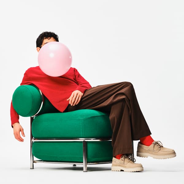 En person sitter i en grön fåtölj. Framför personens ansikte svävar en rosa ballong. 