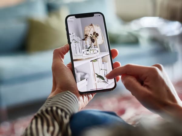 En person som använder sin smarta telefon för att gå in på IKEA appen.