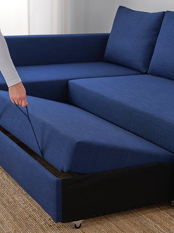 En person trækker en blå FRIHETEN sovesofa ud.