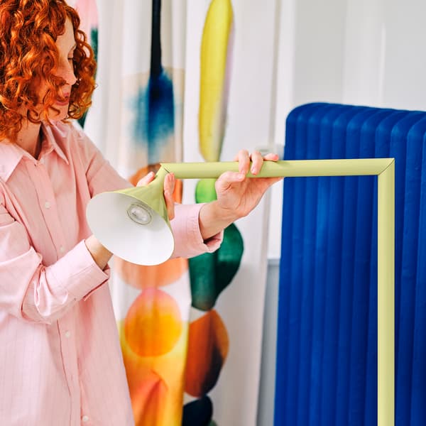 En person vrider på en ljussgul lampa. 