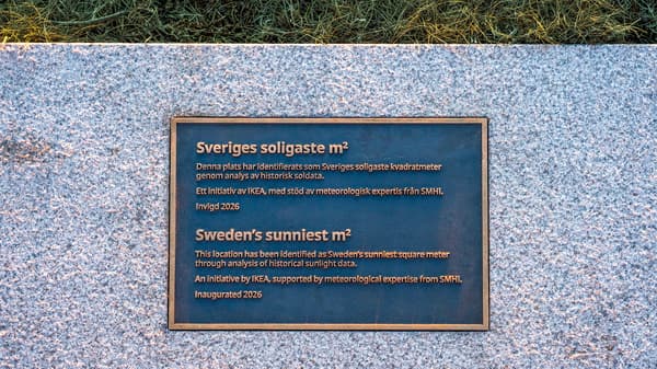 En plakett med inskription sitter på en grå stenplatta. 