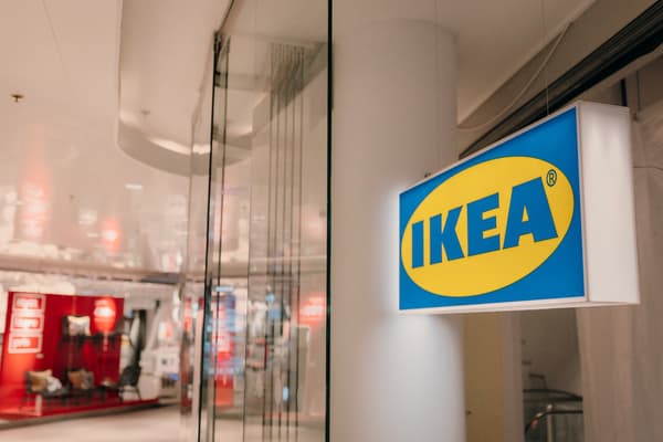 En skylt med en blågul IKEA-logotyp hänger i ett skyltfönster.