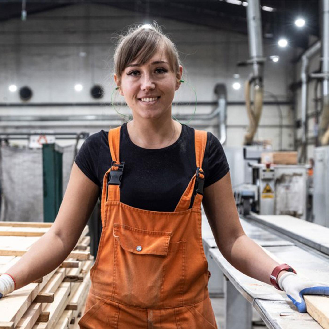 En smilende jente i en oransje snekkerbukse og svart t-skjorte.