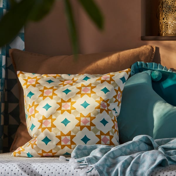 En soffa med turkosa kuddar, inklusive en med ett geometriskt mönster i gult och blått.