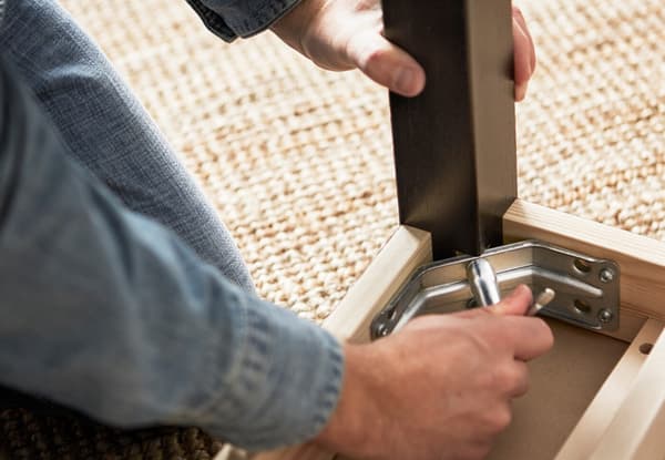 En som etterstrammer et bordben.