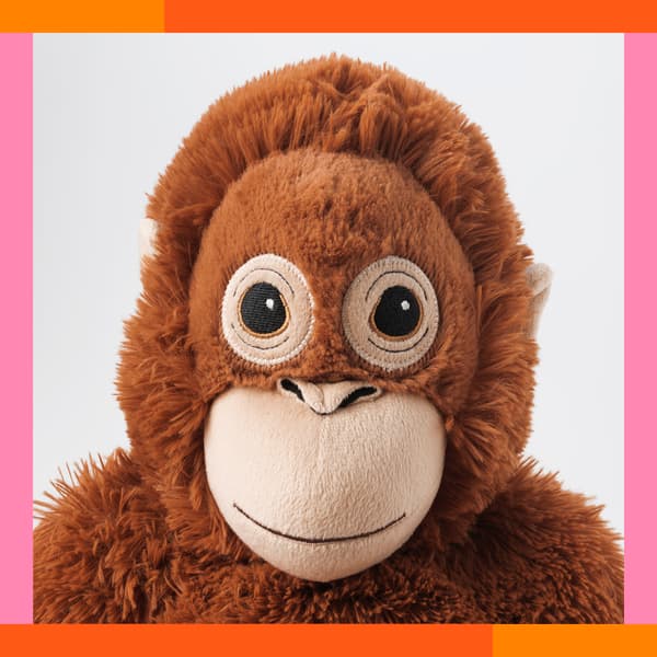 En tøjdyrs orangutang kigger ud igennem en ramme i pink og orange