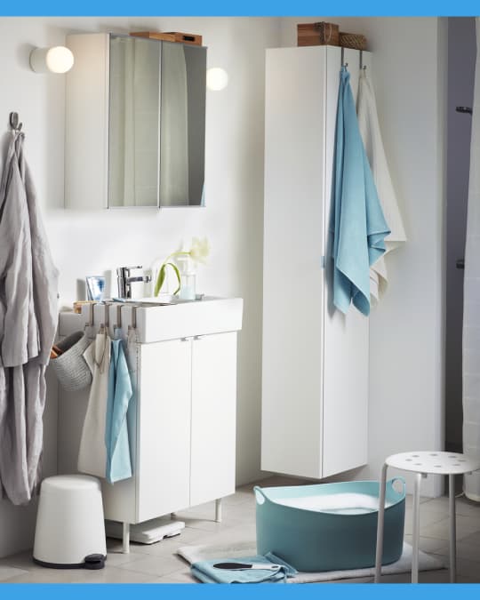 En un baño pequeño se ven toallas, batas y tapetes de baño IKEA de diferentes colores.