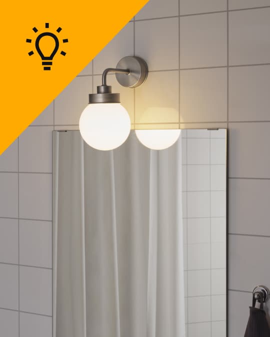 En un baño una lámpara de pared encendida.