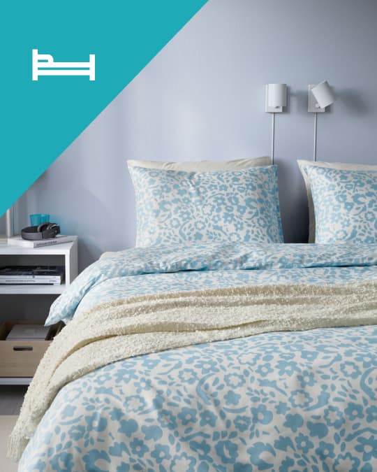 En un dormitiro una cama de dos plazas con ropa de cama floreada en tonos celestes.