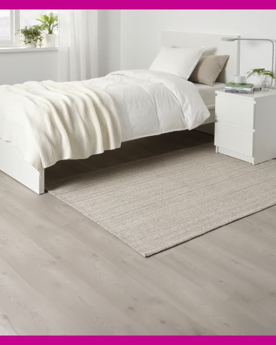 En un dormitorio debajo de la cama doble hay un tapete grande de IKEA.