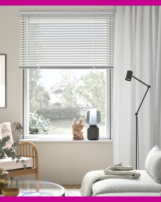 En un living de tonos beige una cortina veneciana está combinada con una cortina de tela.