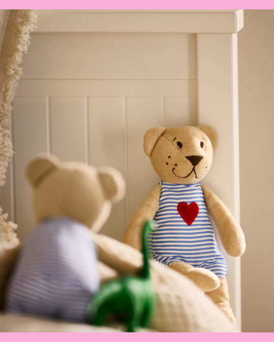 EN una cama hay dos peluches mirándose de frente.