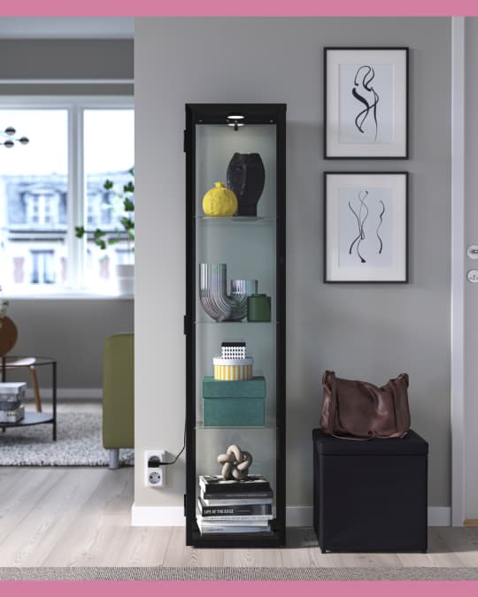 En una pared de una sala una vitrina IKEA con decoraciones en el interior.
