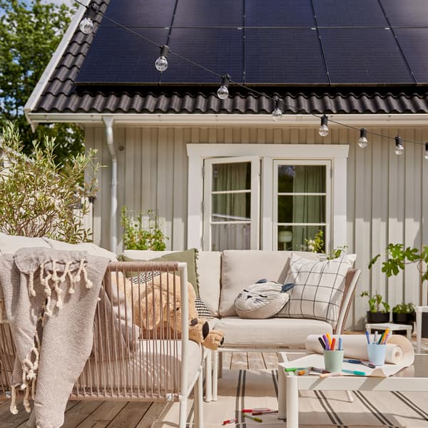 En uteplats framför ett hus med solceller på taket.