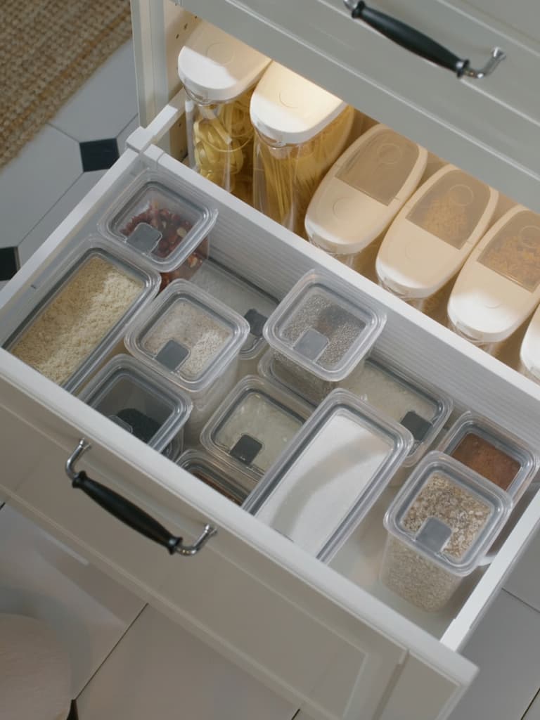 En välorganiserad kökslåda med genomskinliga, lufttäta KLIPPKAKTUS matbehållare som prydligt förvarar diverse torrvaror som pasta och ris.